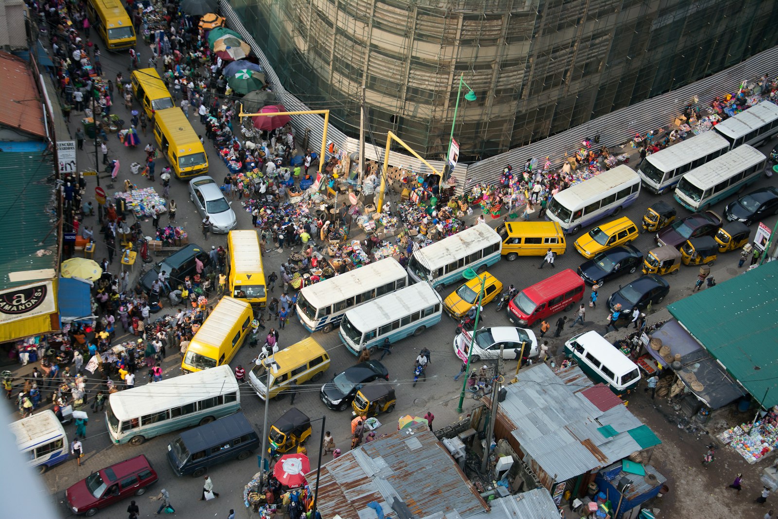 A busy Lagos street seen from above, full of buses, taxis and people